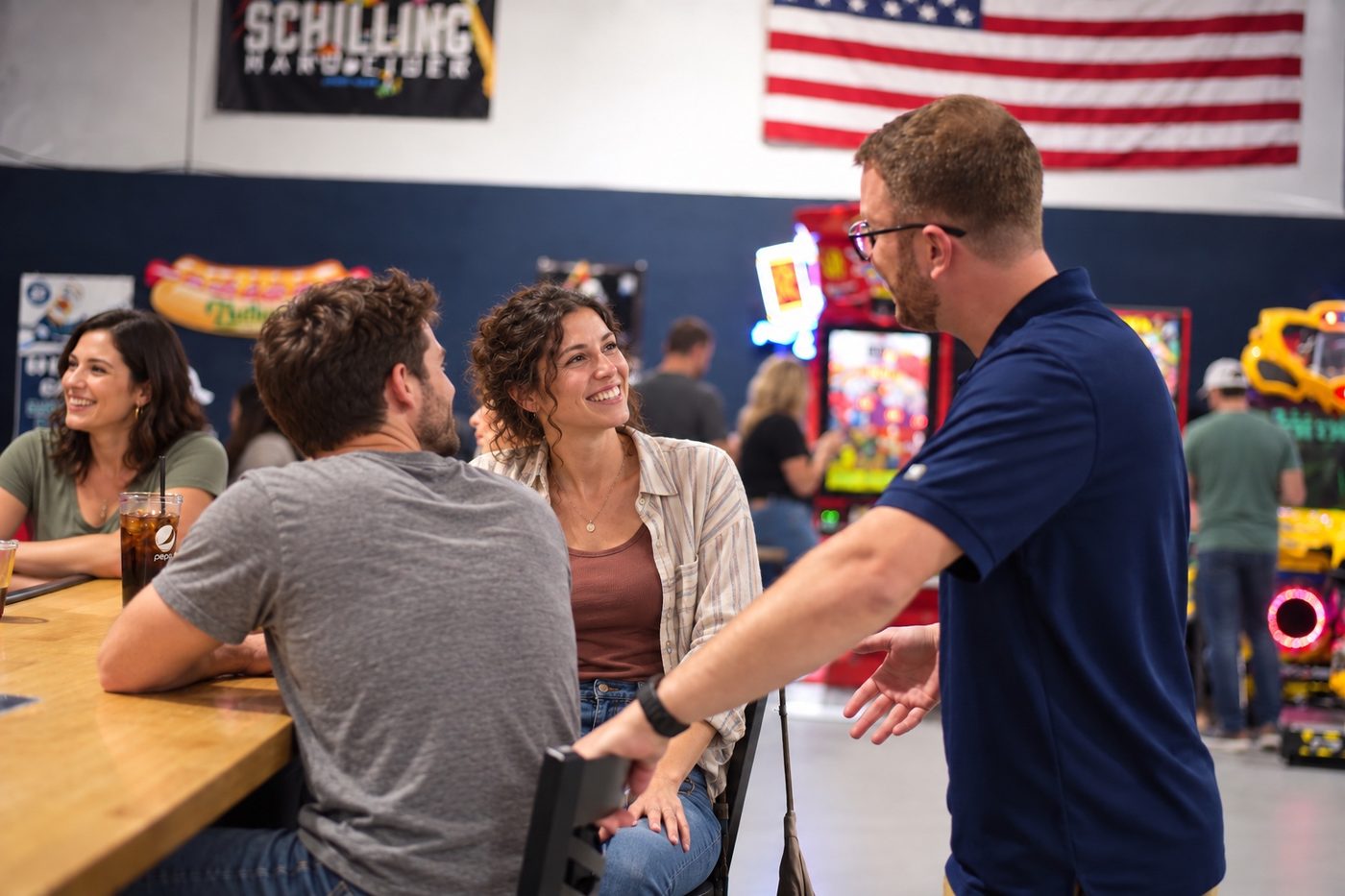 An owner in a Hitters polo talking with seated guests at a table