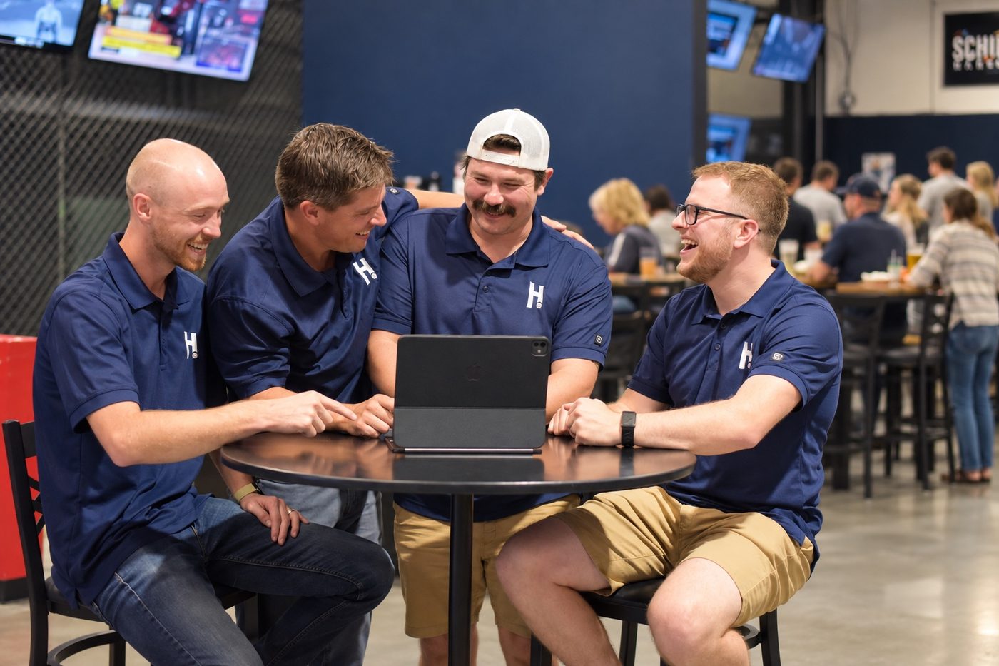 Hitters staff laughing together around a laptop at a table
